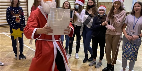 Powiększ grafikę: Mikołaj rozdaje prezenty grupie uczniów.