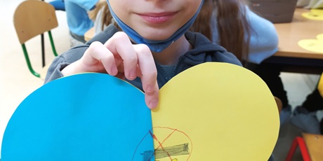Powiększ grafikę: Dziewczynka z żółtym serduszkiem, na którym wykonała obrazek przeciw wojnie.