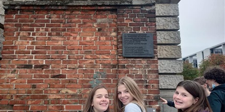 Powiększ grafikę: Trzy dziewczynki na tle  fragmentu muru ze stoczni Gdańskiej.