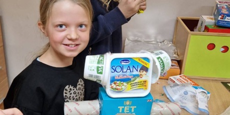 Powiększ grafikę: Dziewczynka w czarnej bluzeczce pokazuje swoją zabawkę wykonaną z materiałów do recyklingu.