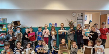 Powiększ grafikę: Grupa uczniów prezentuje swoje prace wykonane z materiałów ekologicznych.