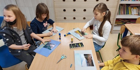 Powiększ grafikę: Dzieci przy stoliku wykonują prace plastyczne.