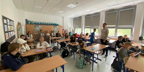 Powiększ grafikę: sala lekcyjna z dziećmi i obserwatorami, przy oknach stoi nauczyciel