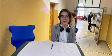 Powiększ grafikę: uczeń siedzący przy księdze pamiątkowej