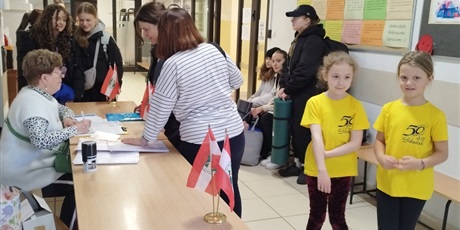 Powiększ grafikę: Organizatorzy i uczestnicy turnieju w szatni szkolnej. na pierwszym planie dwie dziewczynki w żółtych koszulkach.