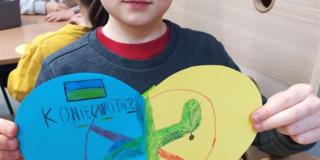 Powiększ grafikę:  Chłopiec pokazuje żółto-niebieskie serca z napisami przeciw wojnie.