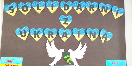 Powiększ grafikę: Tablica z wykonanymi przez dzieci żółto-niebieskimi sercami z napisem "Solidarni z Ukrainą". Poniżej dwa białe gołębie z gałązką pokoju.