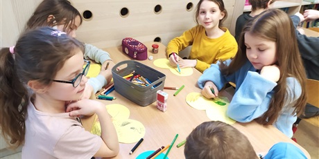 Powiększ grafikę: Dzieci przy stoliku wykonują prace plastyczne (serduszka przeciw wojnie).