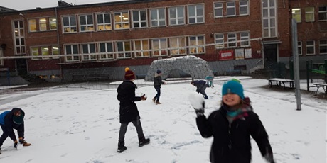 Powiększ grafikę: Dzieci bawiące się śniegiem na boisku szkolnym. W tle budynek szkoły.