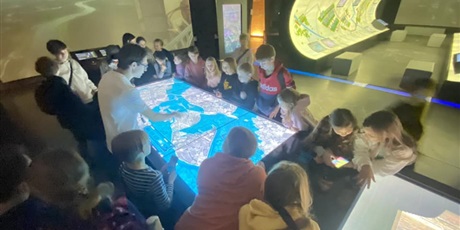 Powiększ grafikę: dzieci pochylają się nad podświetloną mapą mórz i oceanów