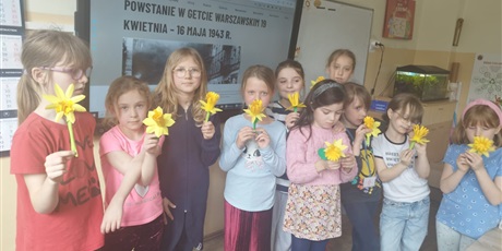 Powiększ grafikę: Grupa uczniów z własnoręcznie wykonanymi żonkilami.