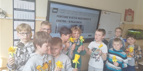 Powiększ grafikę: Grupa uczniów z własnoręcznie wykonanymi żonkilami.