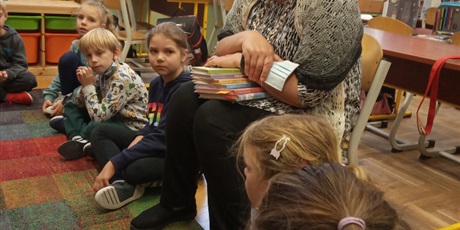 Powiększ grafikę: Dzieci z kl. IIb słuchają czytanej książki przez p. Mirkę z biblioteki. Dzieci siedzą na dywanie.
