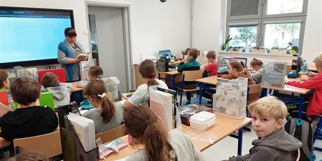 Powiększ grafikę: Dzieci z kl. IIIa słuchają czytanej książki przez p. Mirkę z biblioteki. Uczniowie znajdują się w czytelni.
