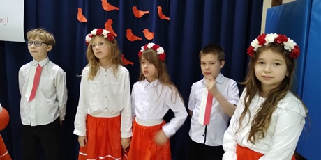 Powiększ grafikę: Uczniowie w odświętnych strojach, dziewczynki w biało-czerwonych wiankach.