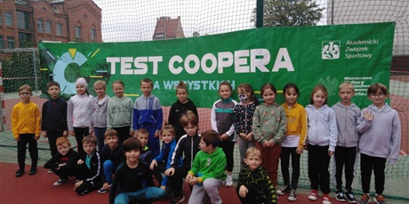 Powiększ grafikę: Uczestnicy testu Coopera na tle banera reklamującego test Coopera