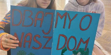 Powiększ grafikę: Dwie uczennice z plakatem "Dbajmy o nasz dom"