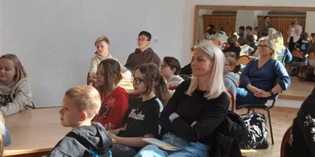 Powiększ grafikę: Uczniowie i nauczyciele siedzą przy stolikach i z uwagą słuchają wykładu.