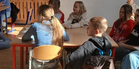 Powiększ grafikę: Uczniowie i nauczyciele siedzą przy stolikach i z uwagą słuchają wykładu.