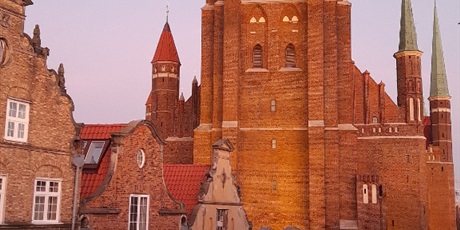 Powiększ grafikę: Bazylika Mariackaw Gdańsku  Zdjęcie wykonane chwilę po zachodzie słońca, stąd różowe zabarwienie fotografii. Połączenie promieni zachodzącego słońca ze sztucznym oświetleniem świątyni daje bardzo cie
