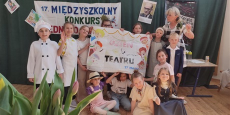 Powiększ grafikę: Uczestnicy konkursu prezentują duży plakat, który wykonali w czasie obrad komisji. Stoją z organizatorką na tle dekoracji.